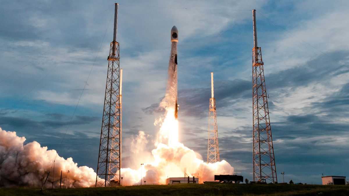 Rocket ship takes off at dusk with lots of flames coming out of booster.