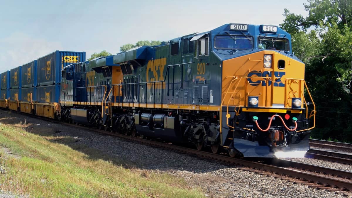 A photograph of a CSX train traveling next to a forest.