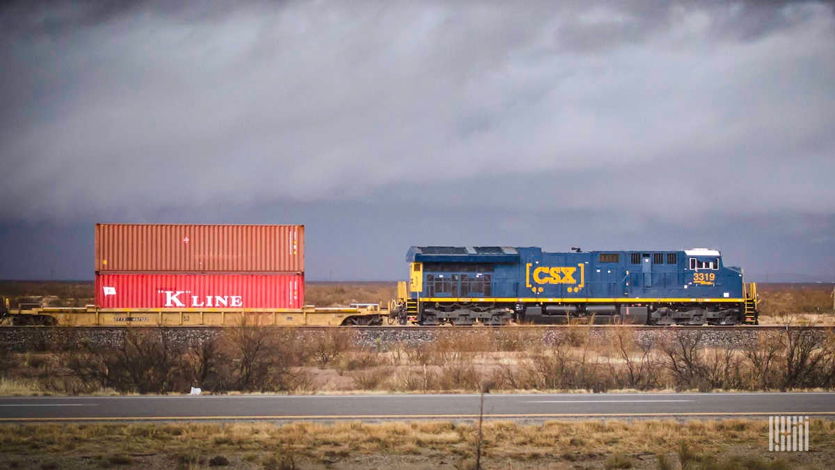 A photograph of a CSX train pulling intermodal containers across a field.