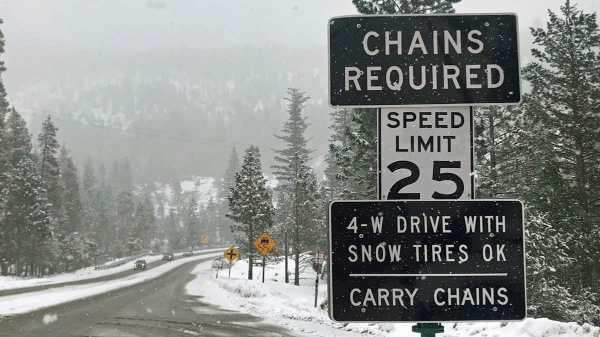 "Chains required" sign along a snowy California highway.