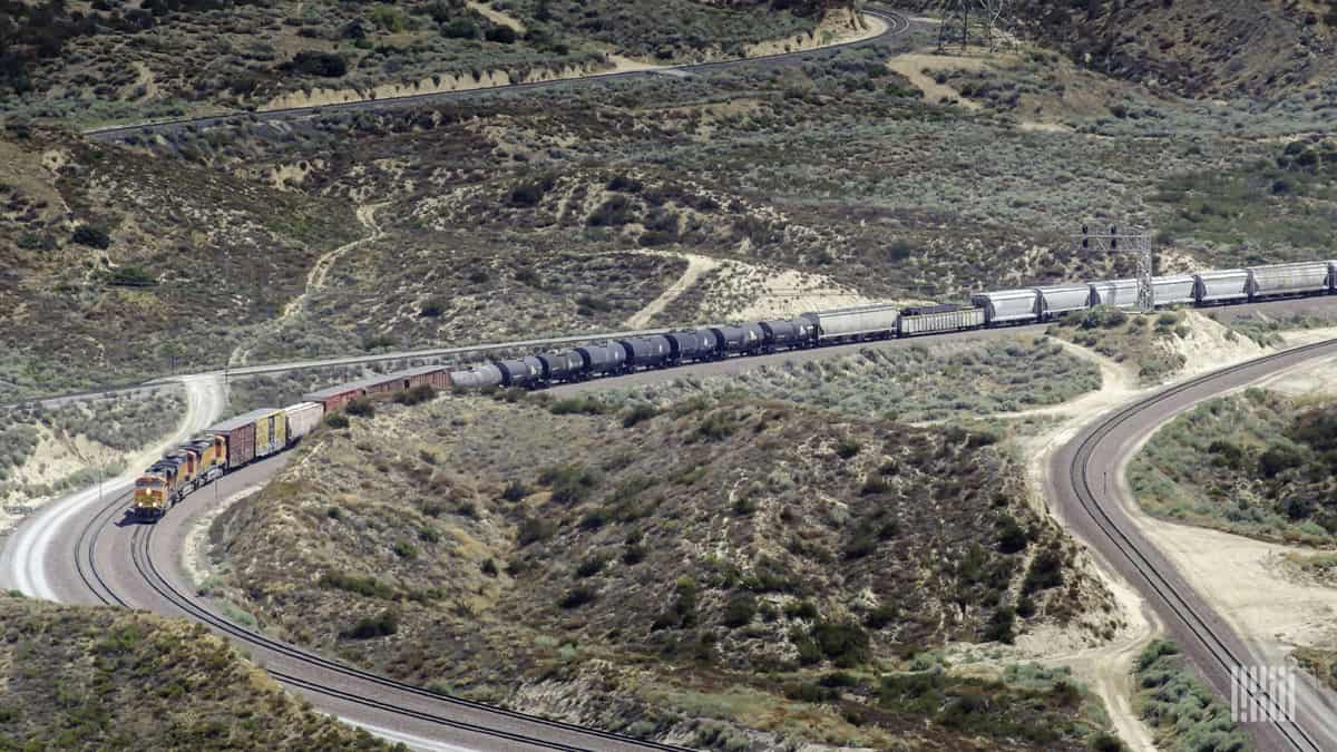 A photograph of a train traveling across a barren mountain range.