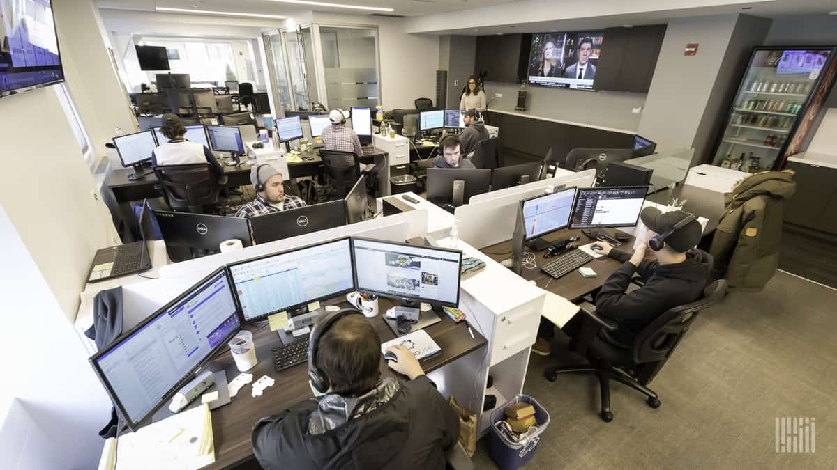 Brokers inside office sitting in front of computer screens