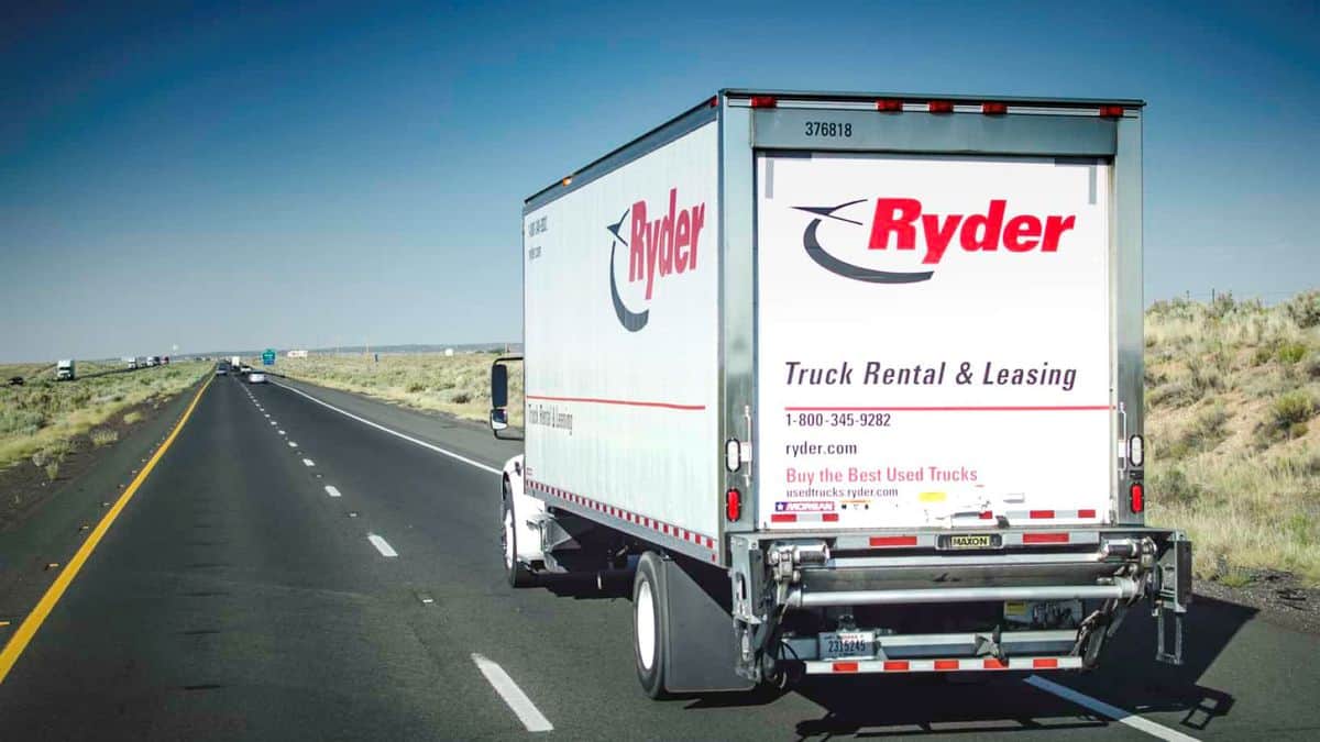 Rear view of white Ryder truck driving down highway on sunny day.