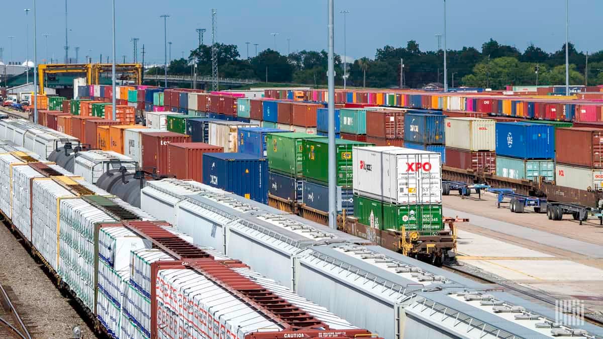 A photograph of intermodal containers and railcars parked in a rail yard.