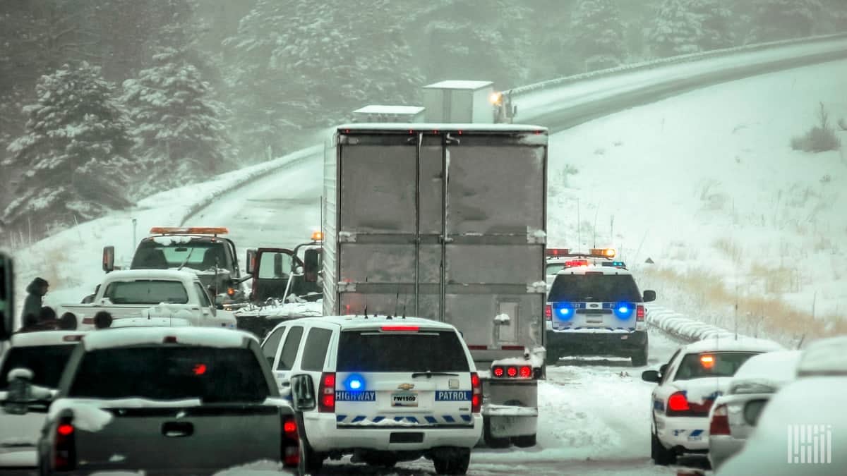 Tractor=trailers and cars in a traffic jam on a snowy highway.