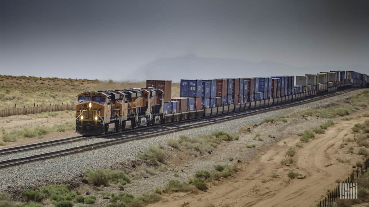 A photograph of a train driving through a desert.