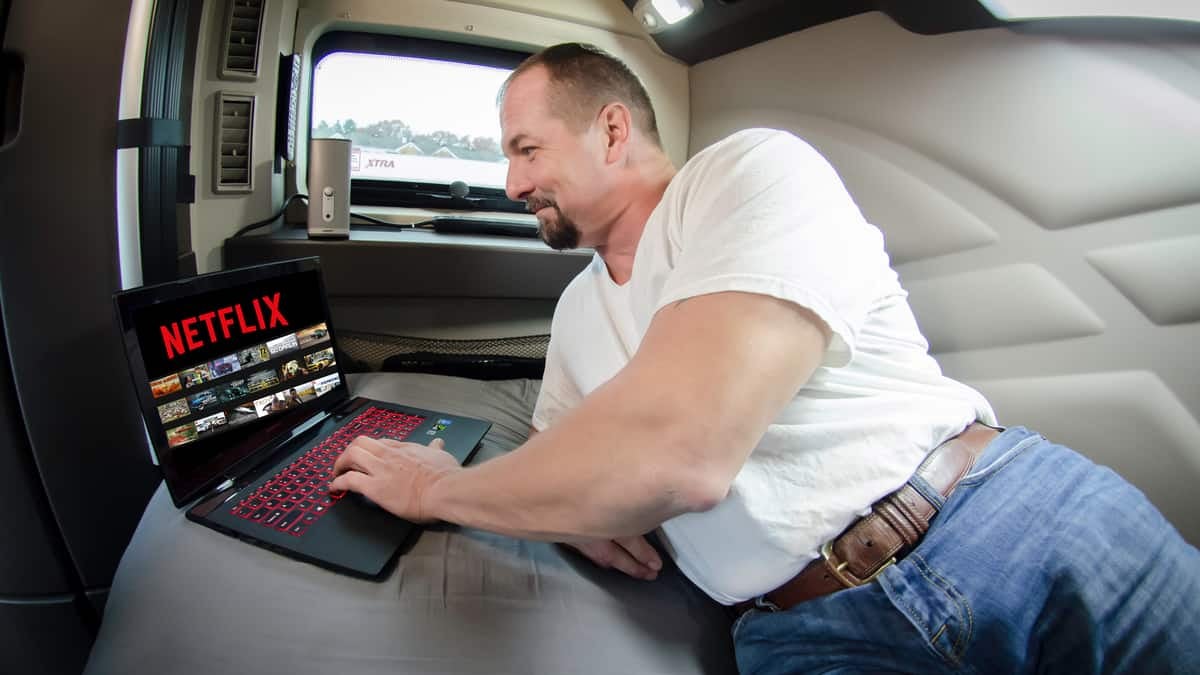 Truck driver in his sleeper selecting a streaming movie to watch.