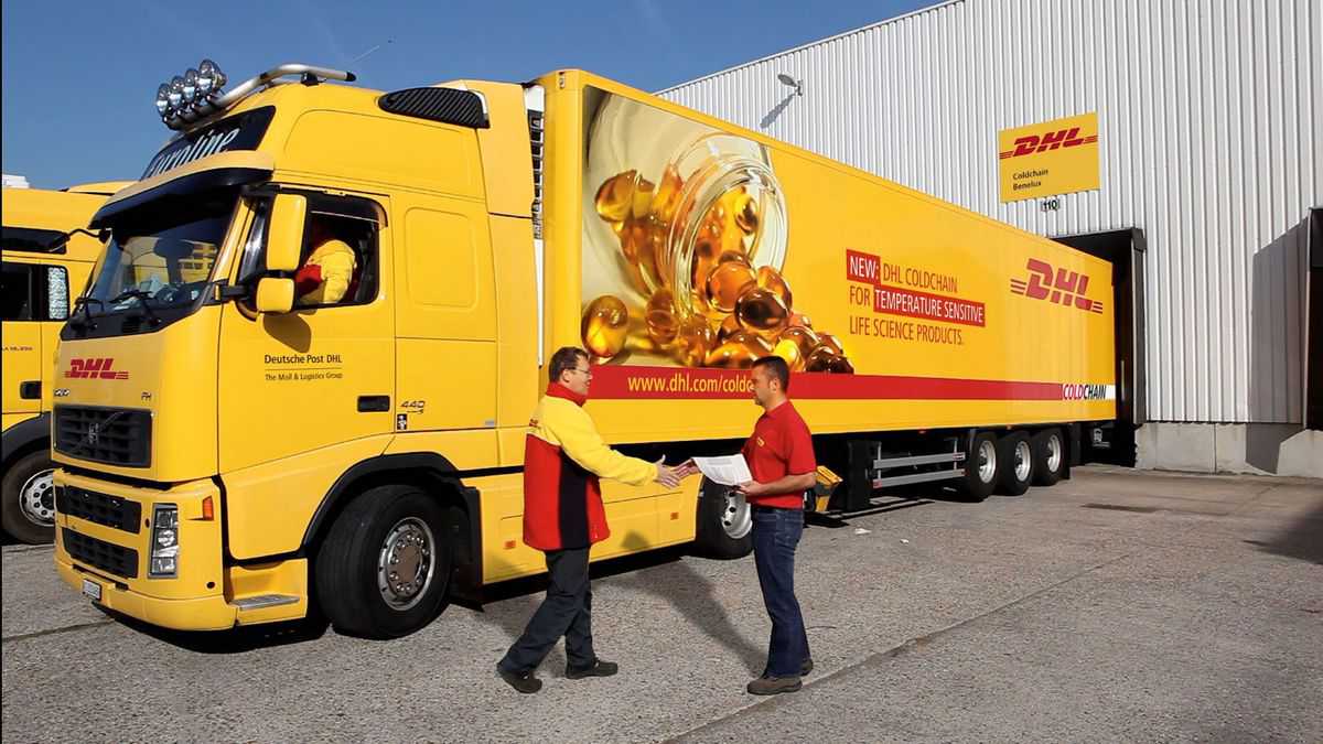 A bright yellow refrigerated DHL truck backed up to loading dock.