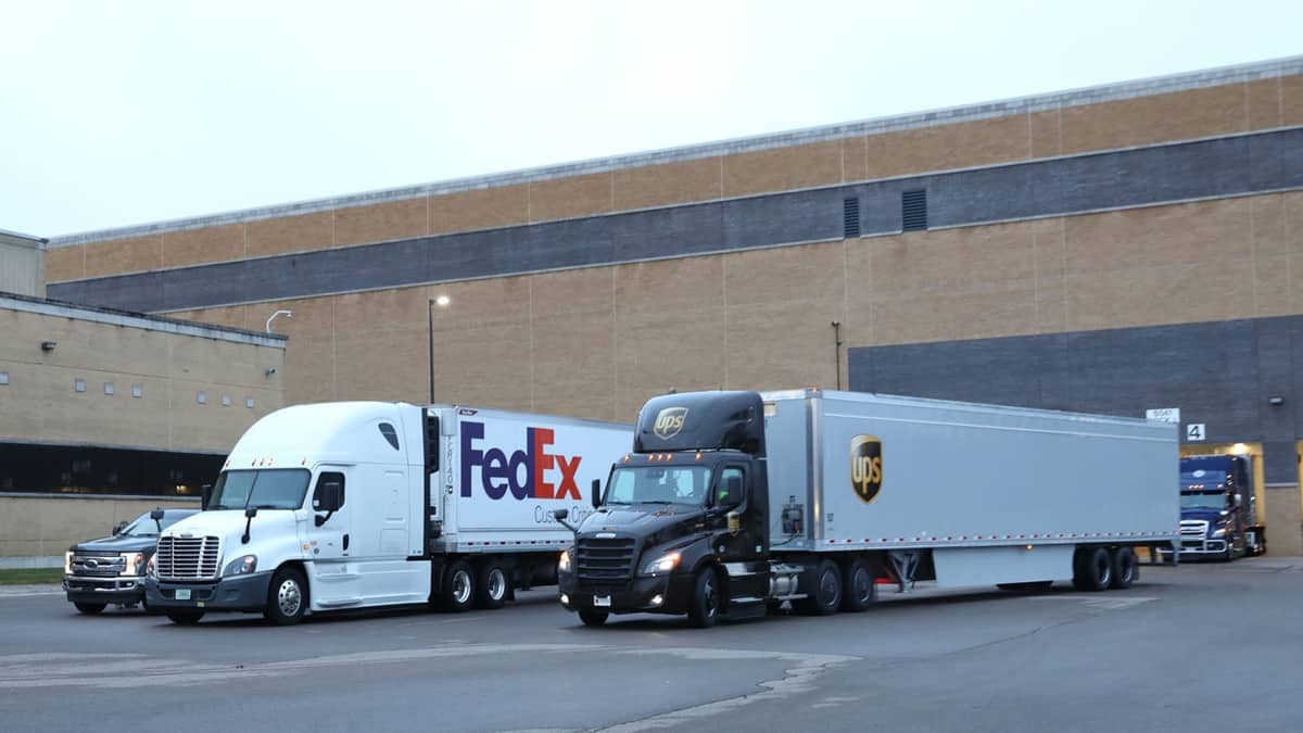 A FedEx and UPS tractor trailer at a loading dock.