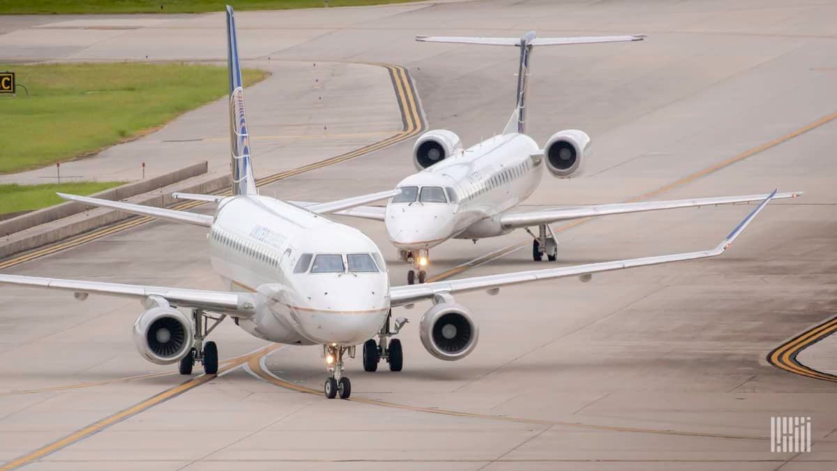 Two small regional jets taxi on airport roadway.