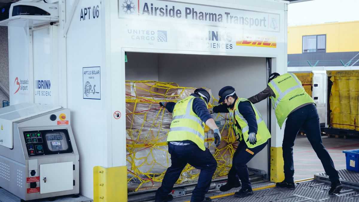 A ground crew pulls out a pallets from a big air shipping container.