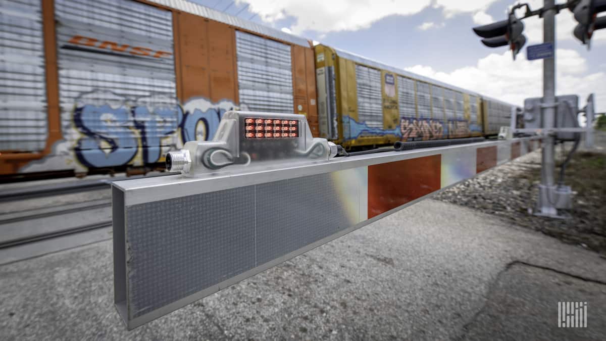 A photograph of railcars passing by a railroad crossing.