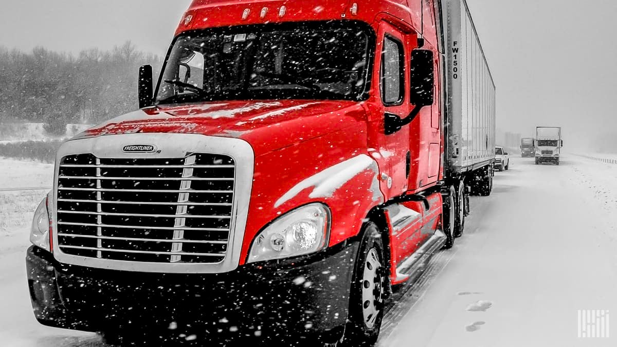 Tractor-trailers stopped on a snowy road.