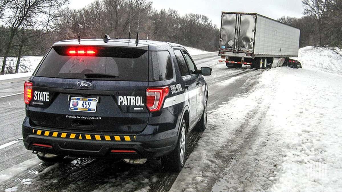 Law enforcement on scene of tractor-trailer accident on snow Wisconsin road.