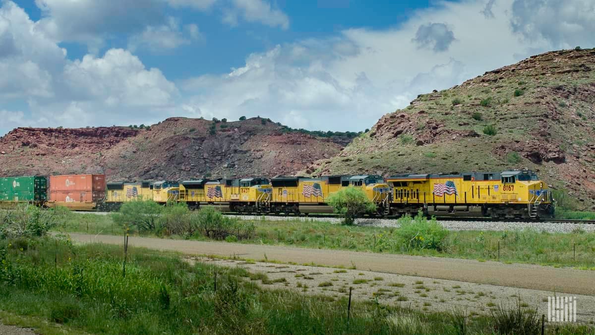 A photograph of a Union Pacific train hauling intermodal containers across a desert.