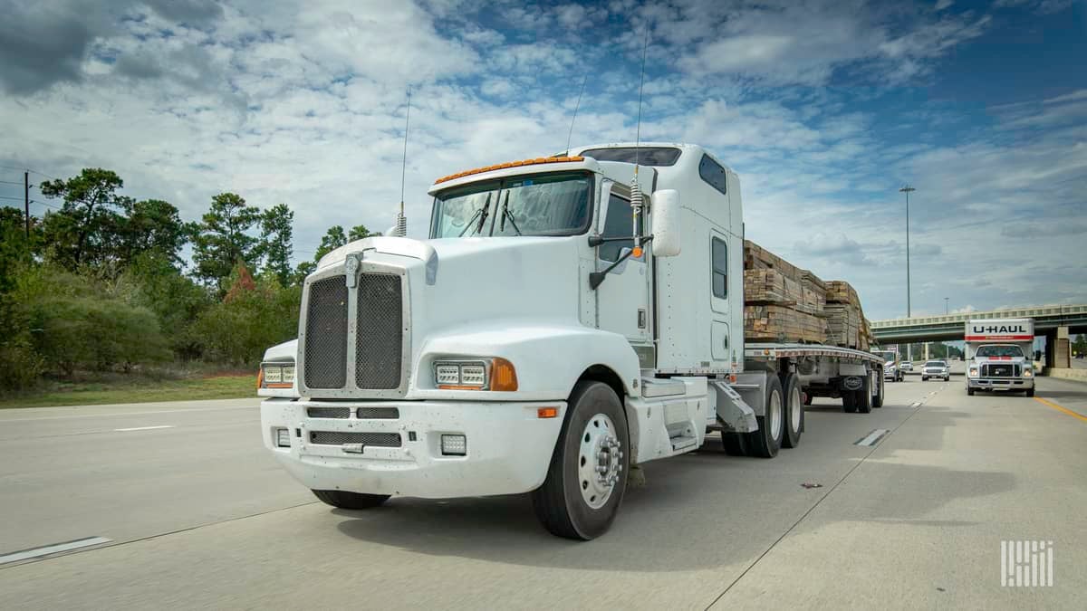 A front view of a truck hauling a trailer with lumber. Canadian trucking company BLB shut down recently.