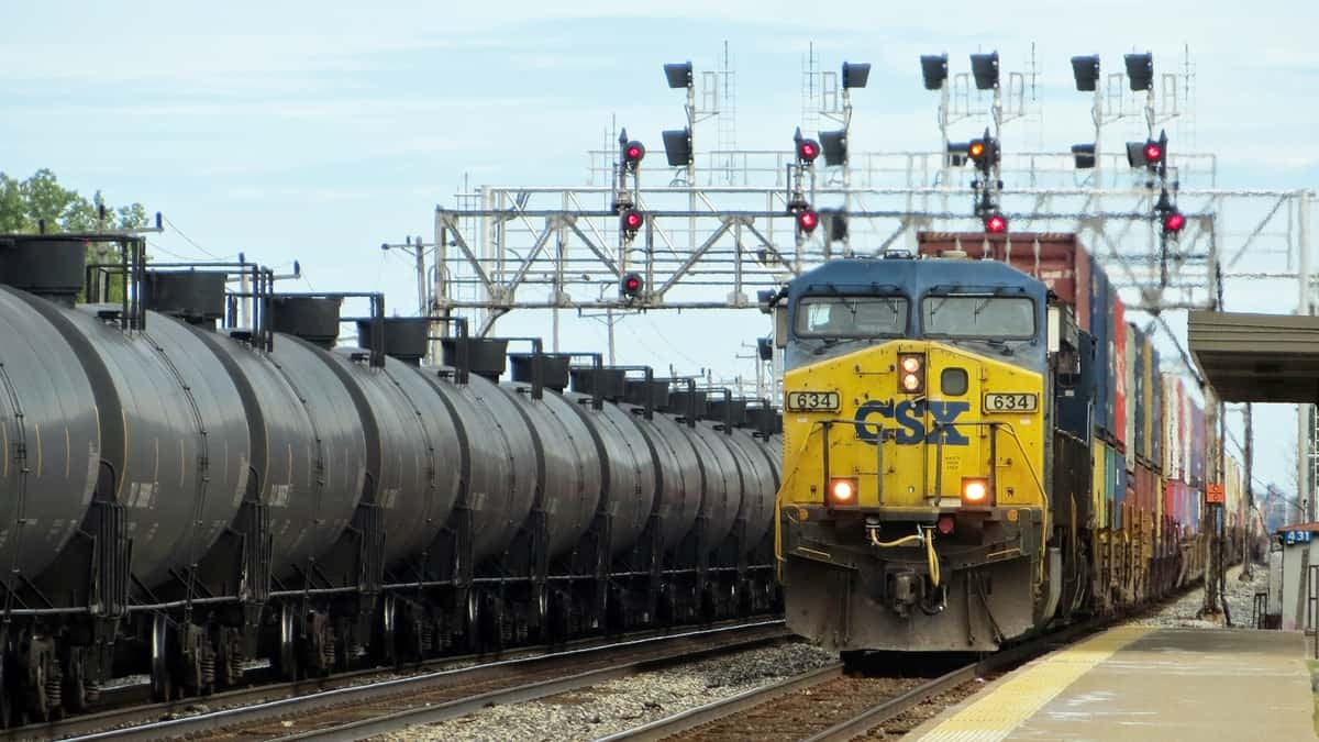 A CSX train sits next to a train consisting of tank cars.