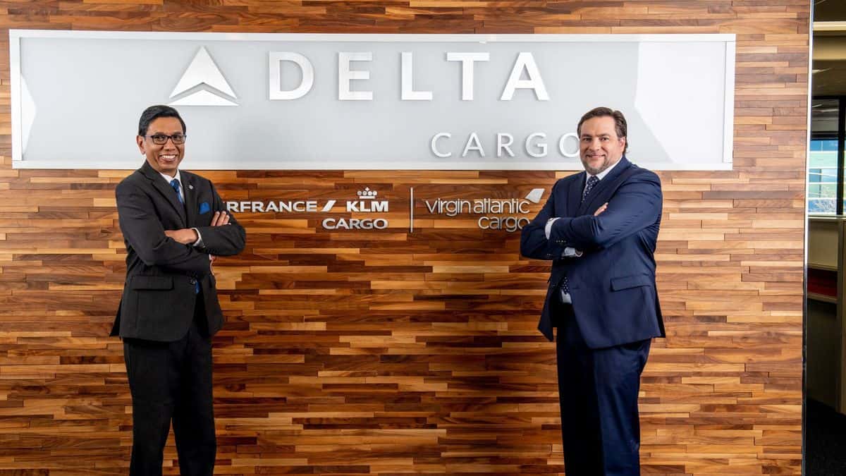 Delta Cargo executives standing in front of company sign at office.