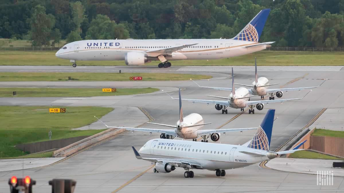 Line of planes in queue on taxiway wait to takeoff.