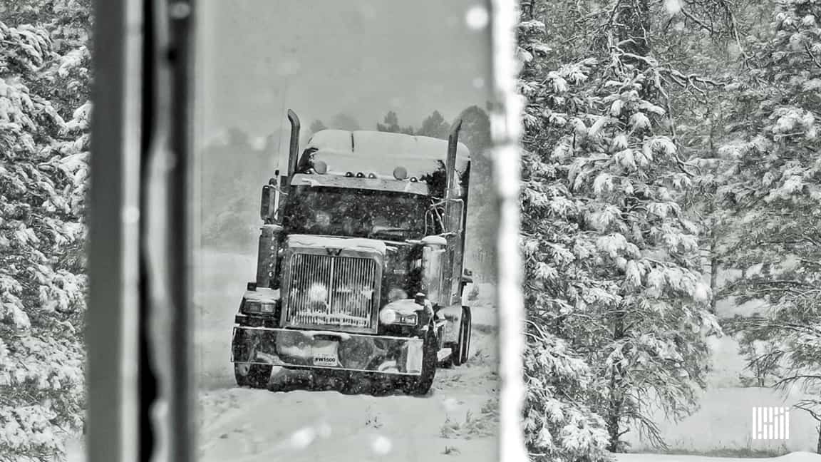 Tractor-trailer heading through snowstorm.