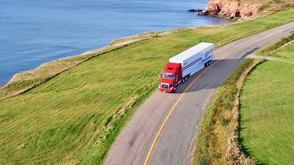 A photograph of a truck driving by a lake.