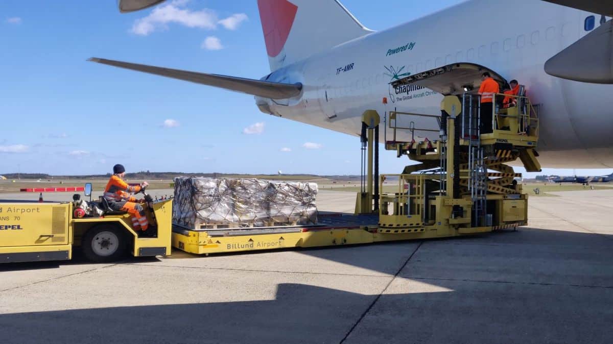 Large dolly delivers pallets to side of plane for tail loading.