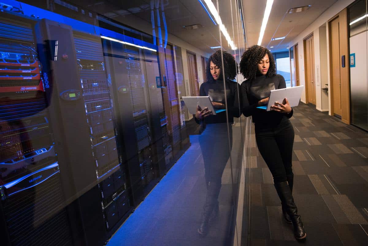 Woman standing outside server room holding laptop