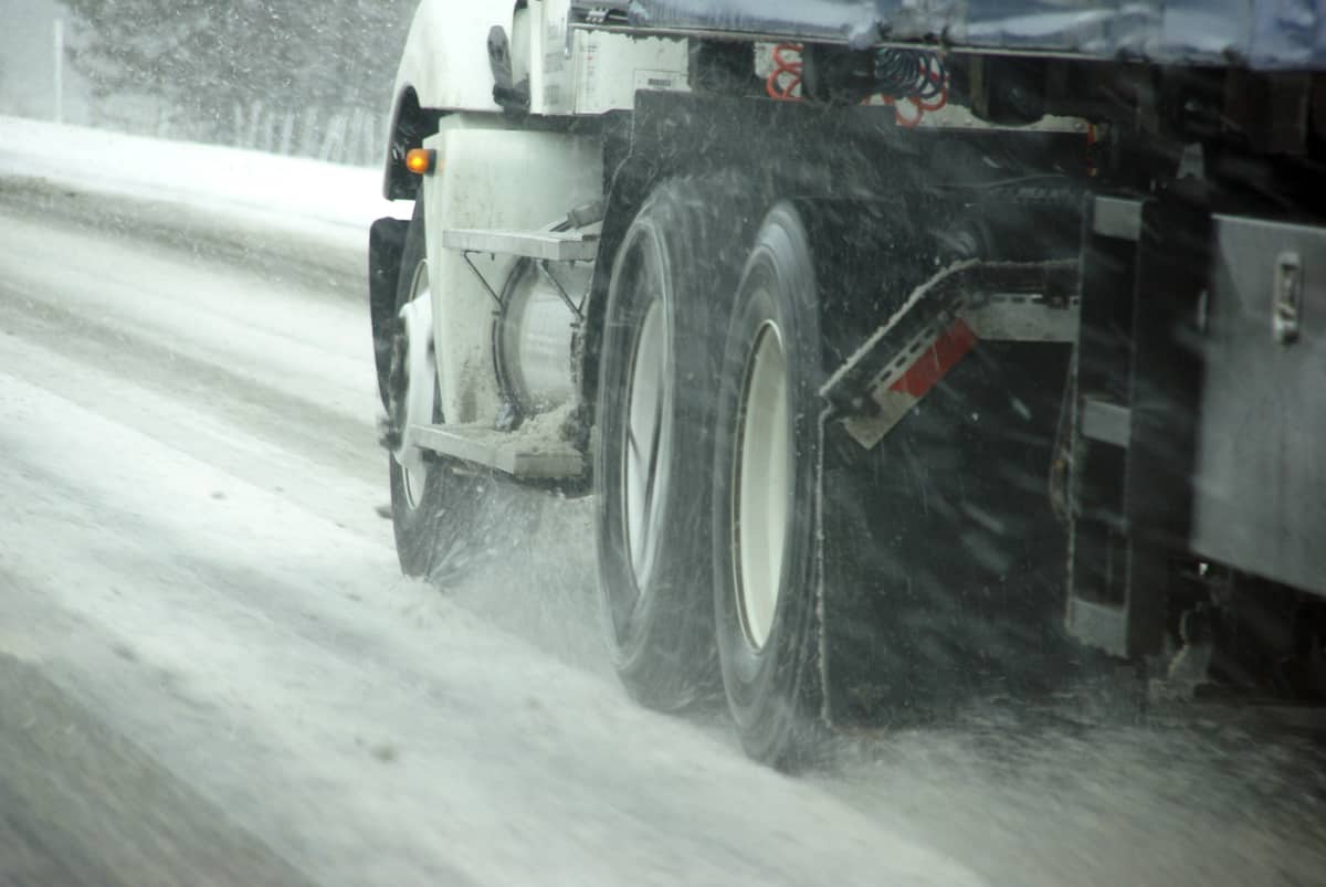 Tractor-trailer heading down slushy/icy road.