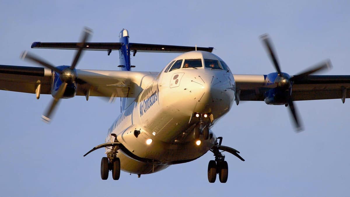 A turboprop ATR plane comes in for landing, view from straight on below the plane.