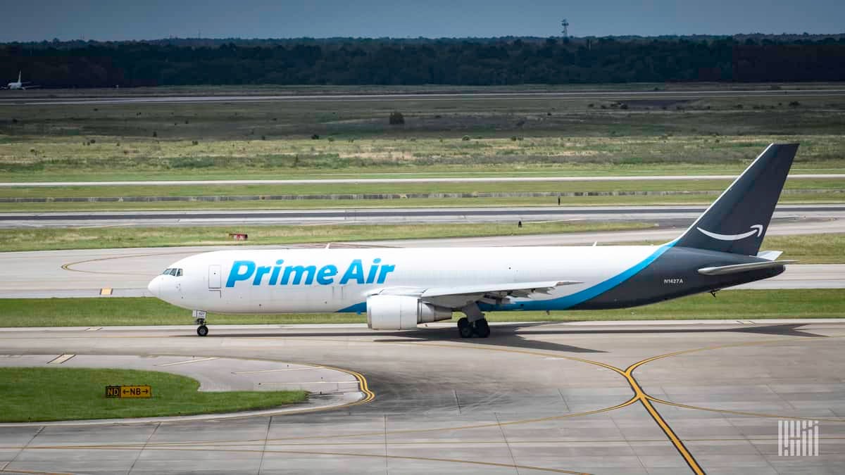 A white Amazon Air jet with blue tail, side view on runway.