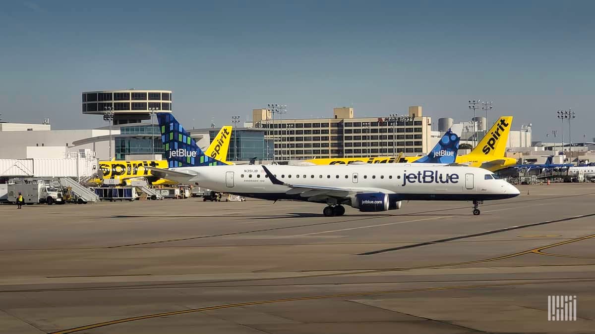 A small white and blue jet on the tarmac with a yellow jet in the background.