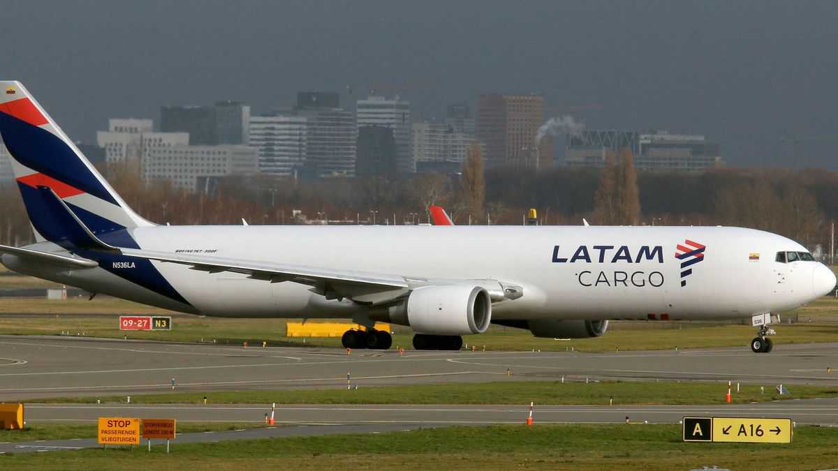 A white LATAM Airlines with blue and red tail on the taxiway at airport.