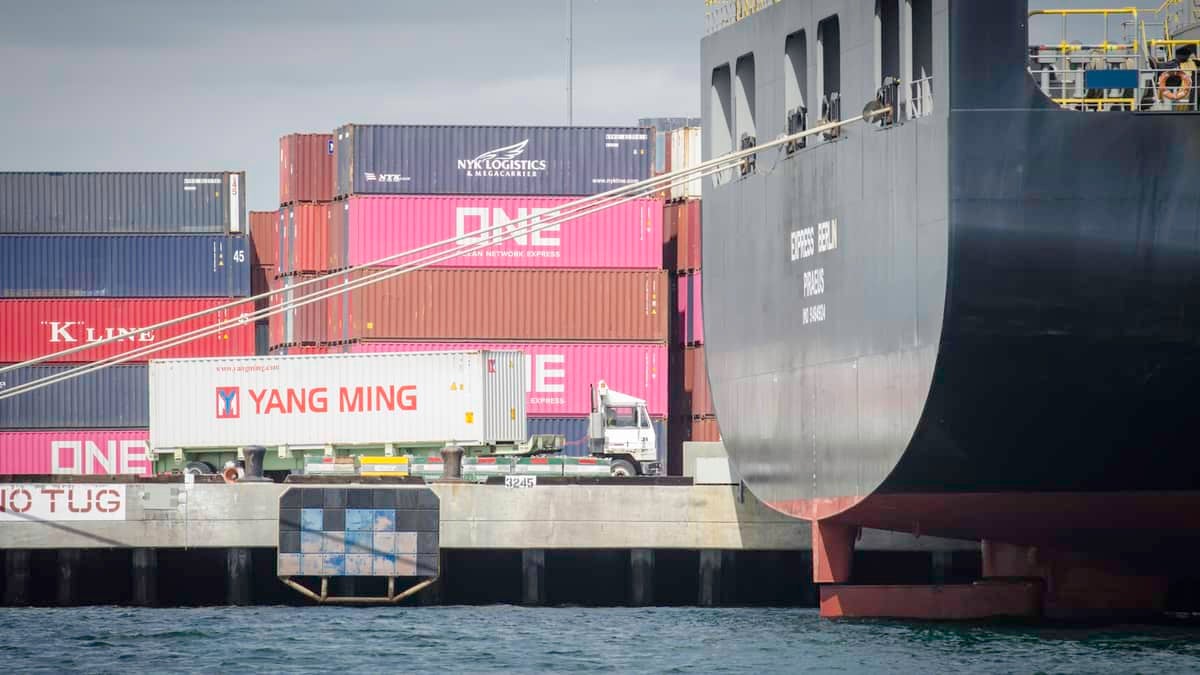 Waterside view of docks stacked with containers and back of a big ship.