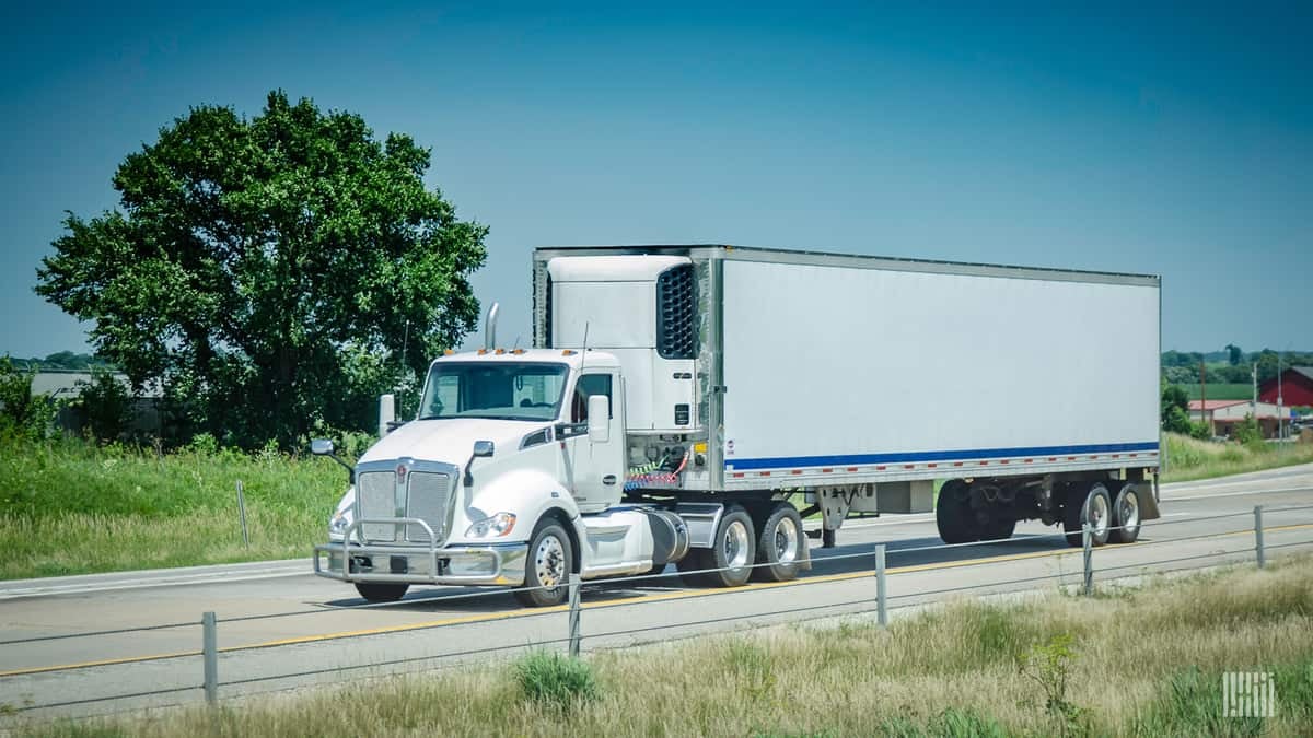 White reefer truck driver on highway under clear blue sky