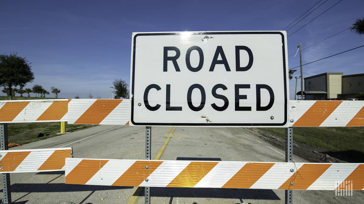 Highway blocked by "Road Closed" barricade.