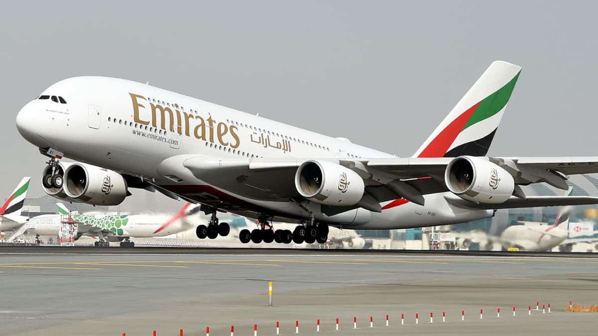 A big, big Emirates A380 jumbo jet lifts off with front wheels off the runway.