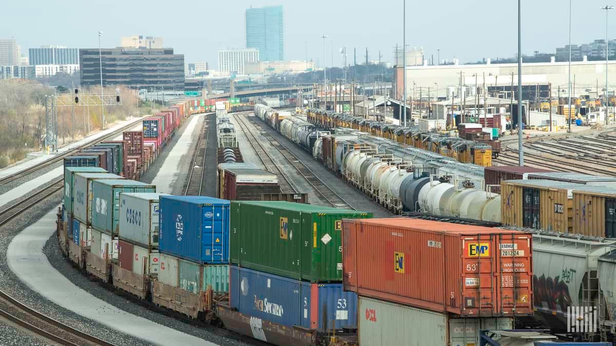 A photograph of a rail yard with a city skyline in the distance.