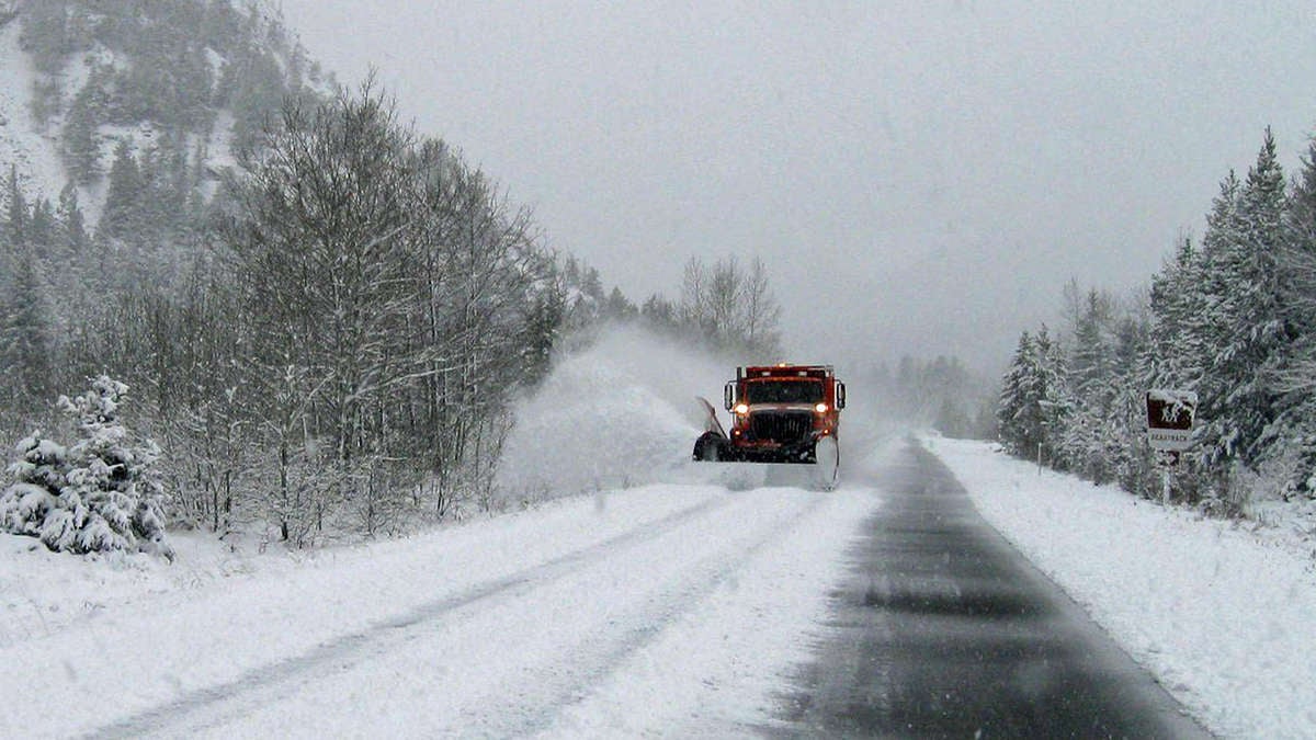 Plow truck clearing snowy Montana highway.