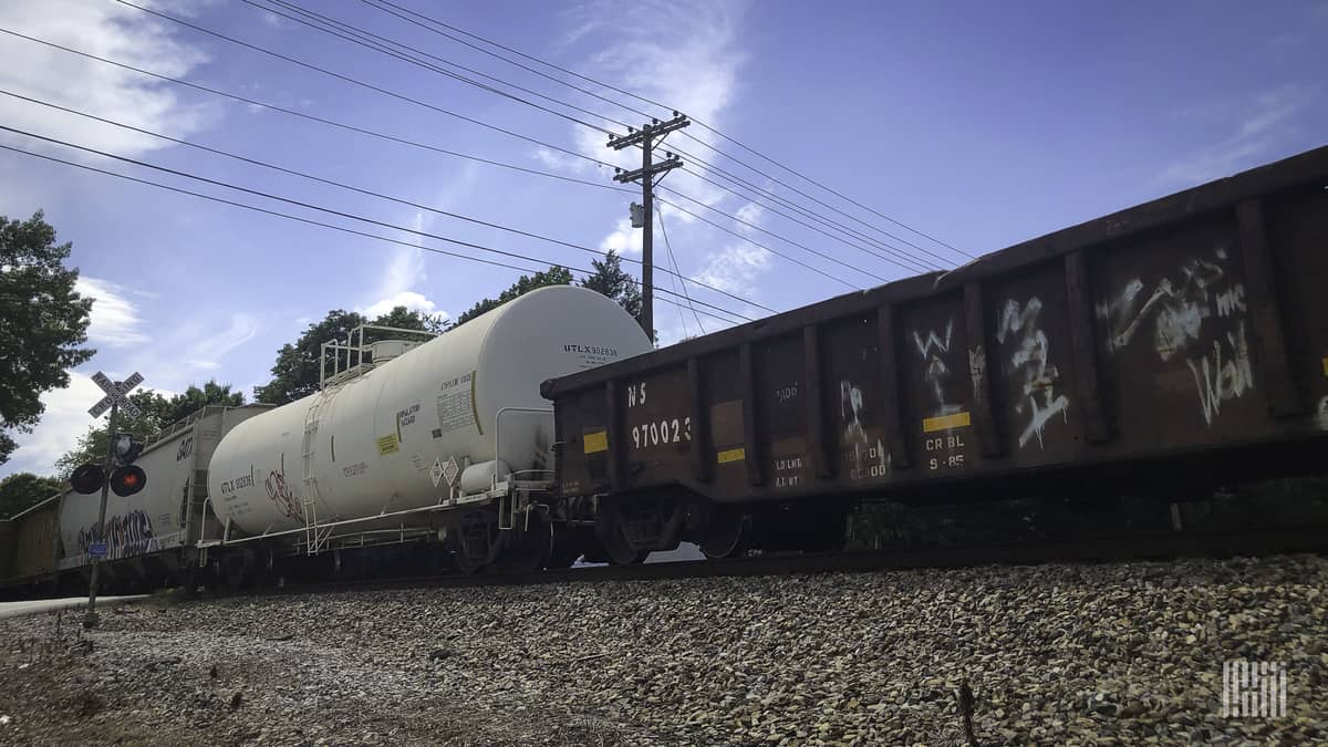 A photograph of rail cars rolling by a railroad crossing.