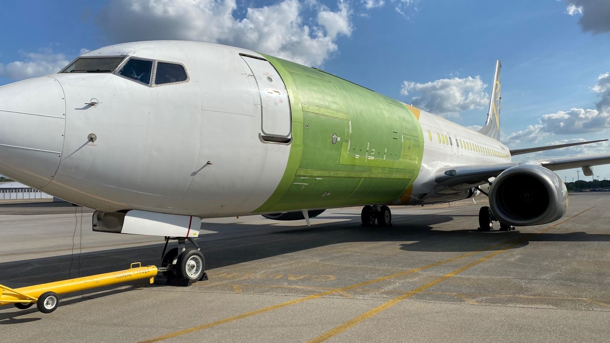 An unpainted Boeing 737-800 with a wider cargo door cut into the side during modification work.