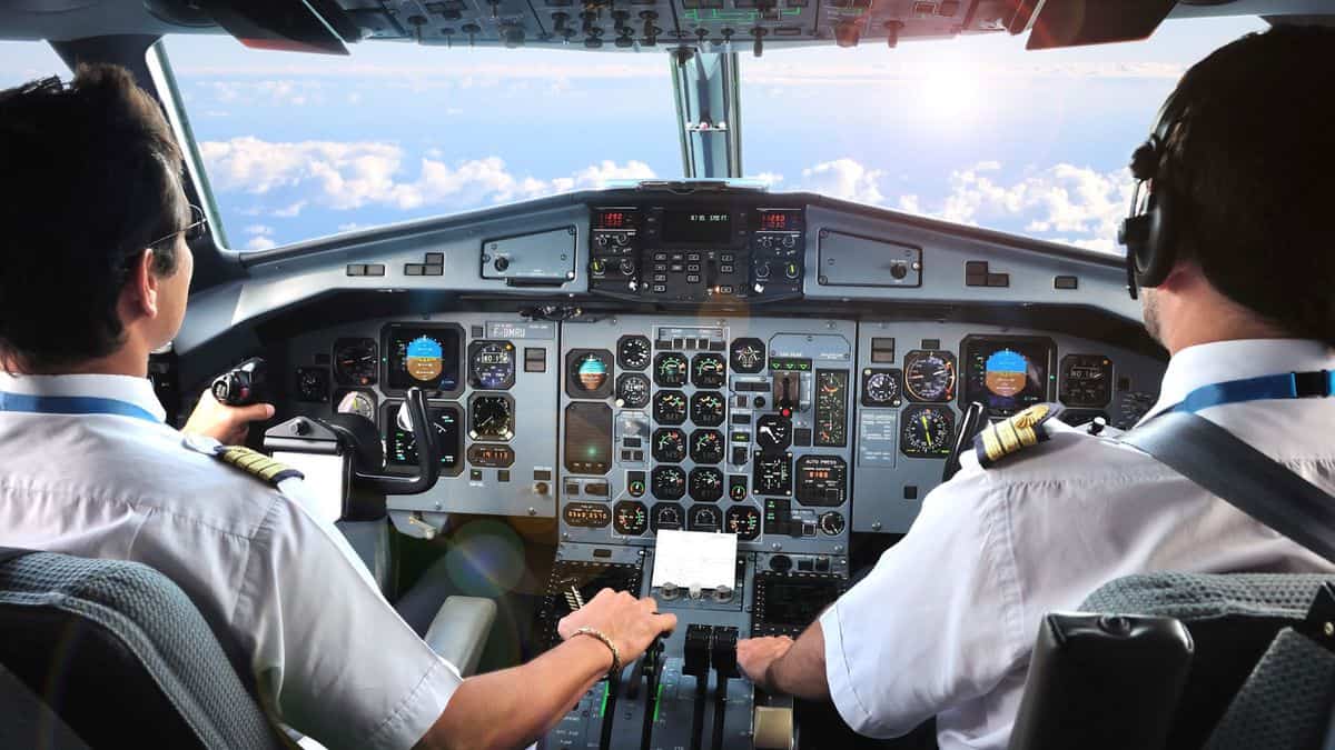 Pilots flying a plane, cockpit view from behind looking out.