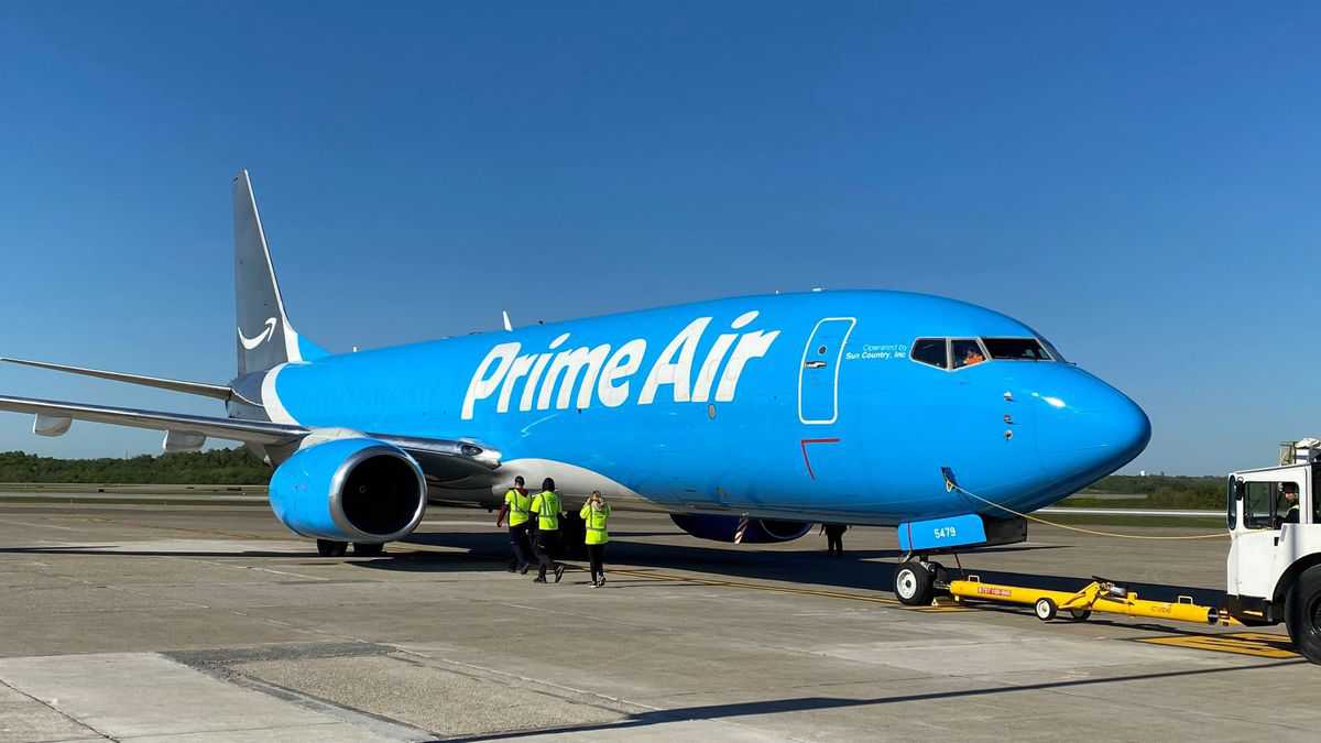 A light blue Amazon Air 737 freighter parked with pusher vehicle.