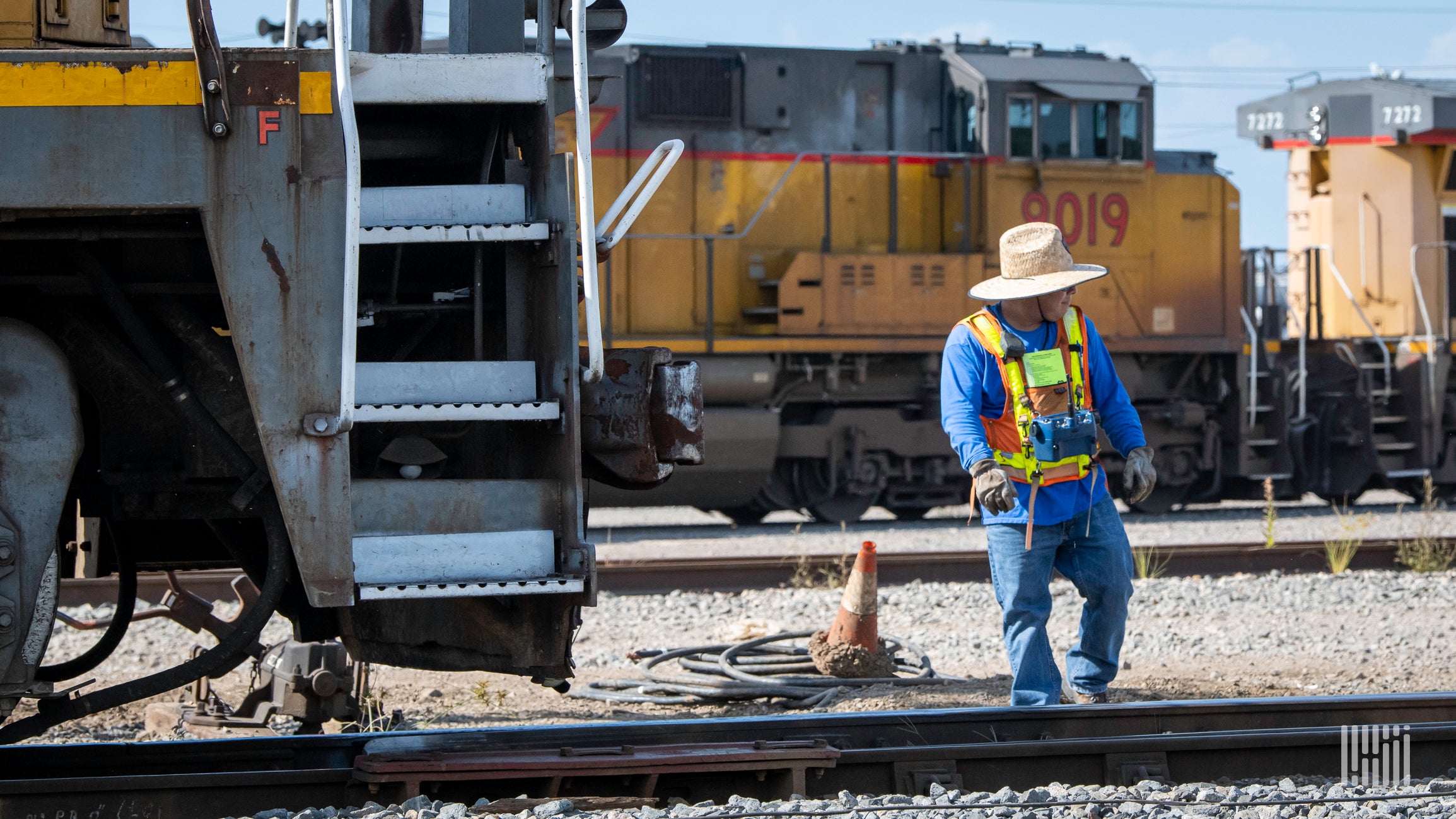 A railroad worker stands in a rail yard.