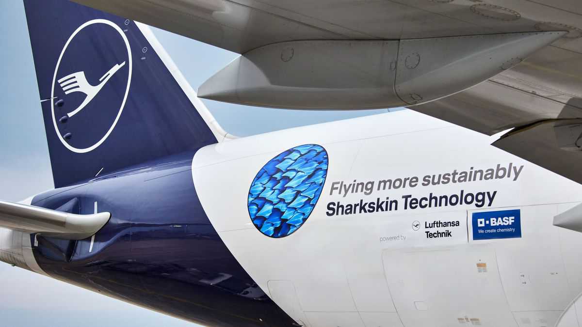 Close up a Lufthansa aircraft tail with logo about "shark" skin technology for better aerodynamics.