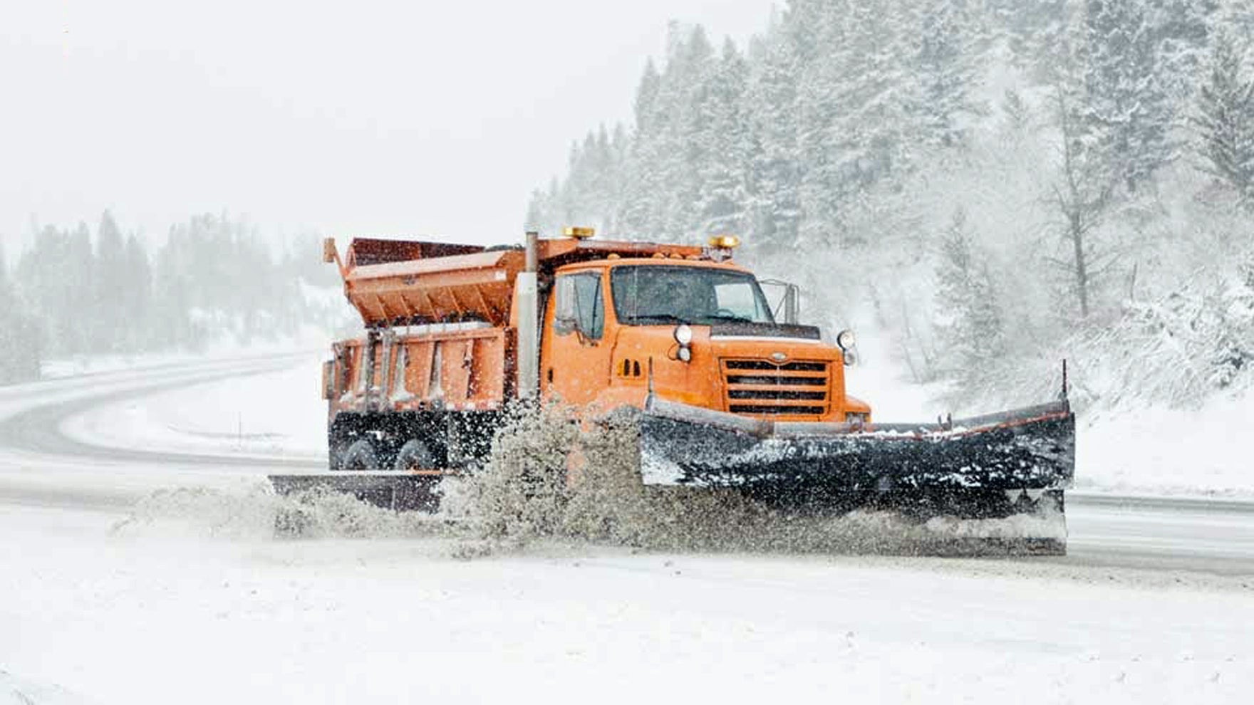 Plow truck clearing snowy Montana highway.