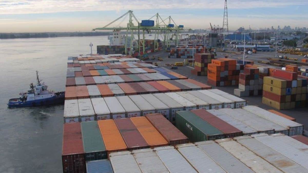 A tugboat helps park a large containership at the Port of Montreal. by pushing it into the wharf.