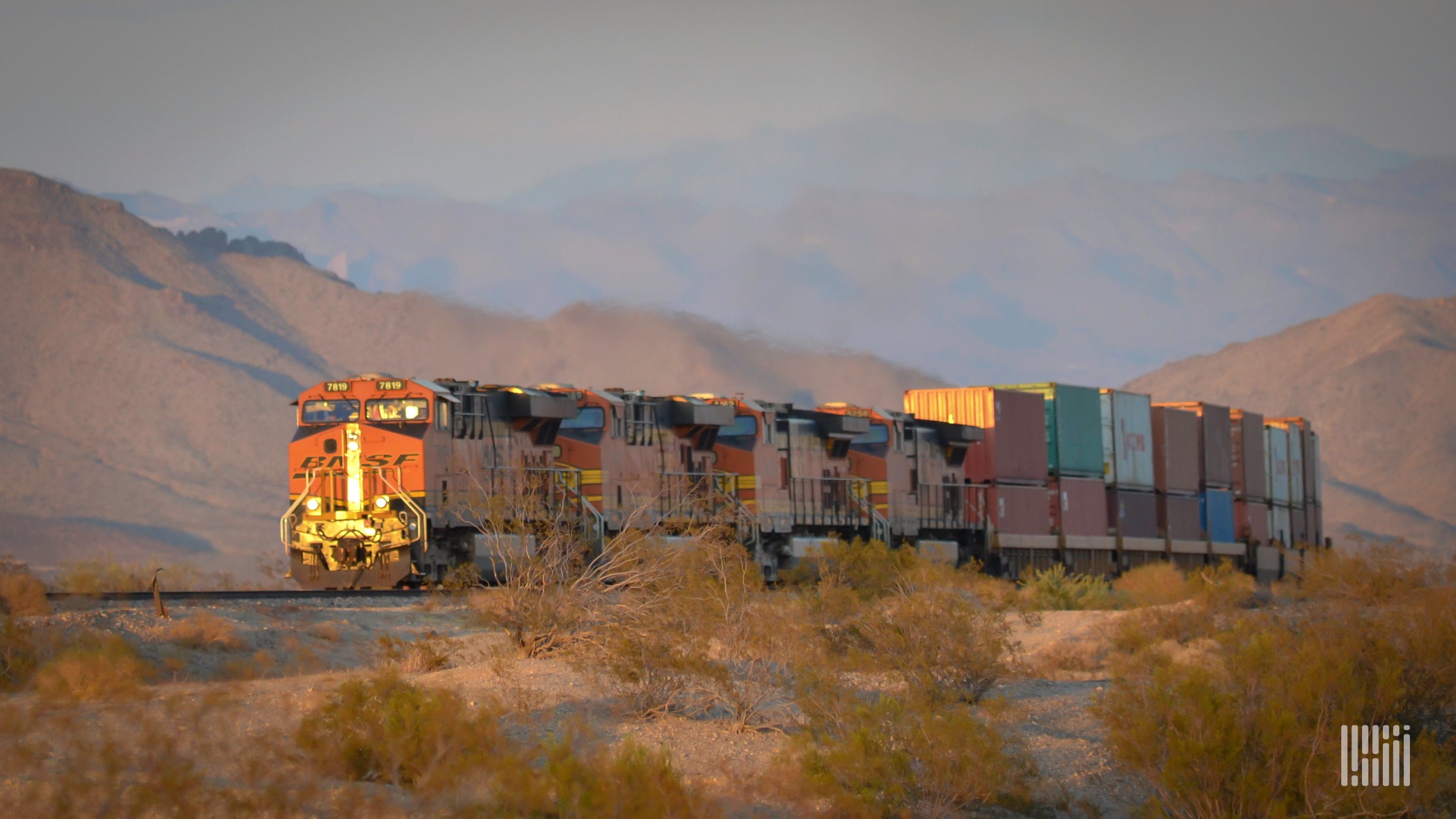 A photograph of a BNSF train hauling intermodal containers across a field.