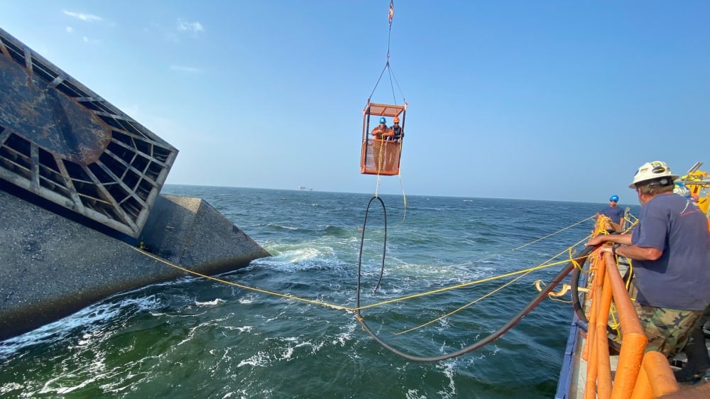 Salvage divers transport a hose to the SEACOR Power fuel tank to start removing the fuel.