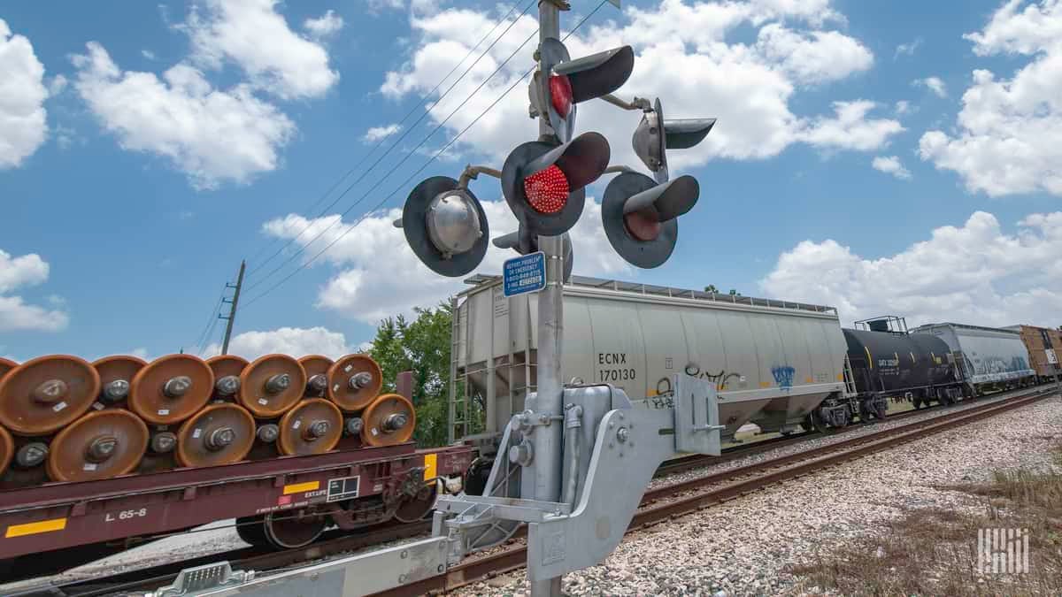 A photograph of a train at a railroad crossing.