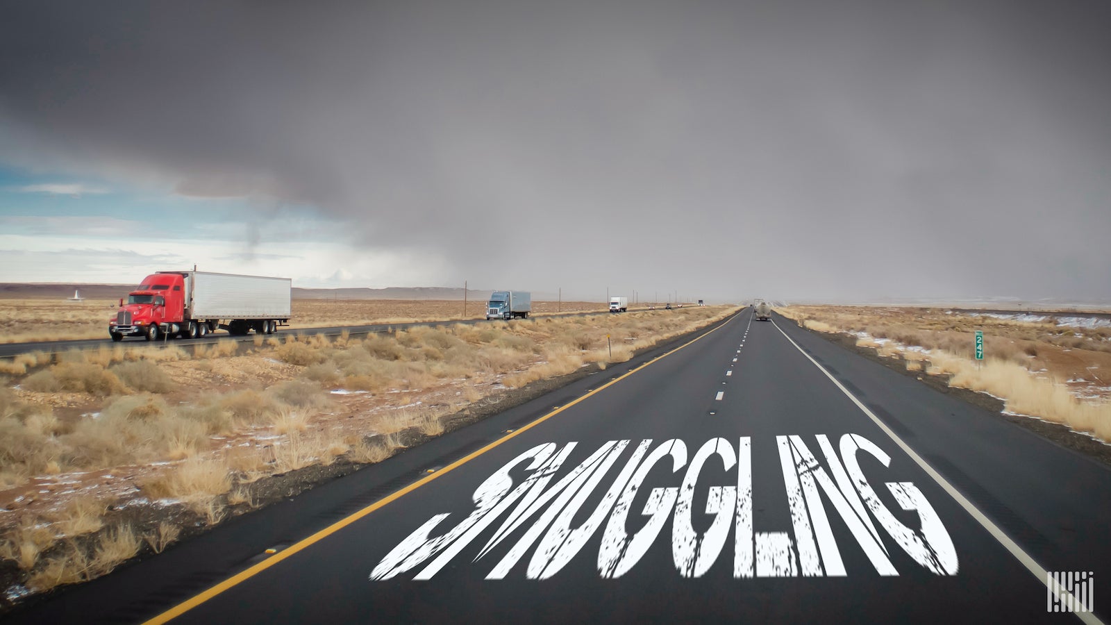 A image of the word 'smuggling' on a highway as truck pass by.